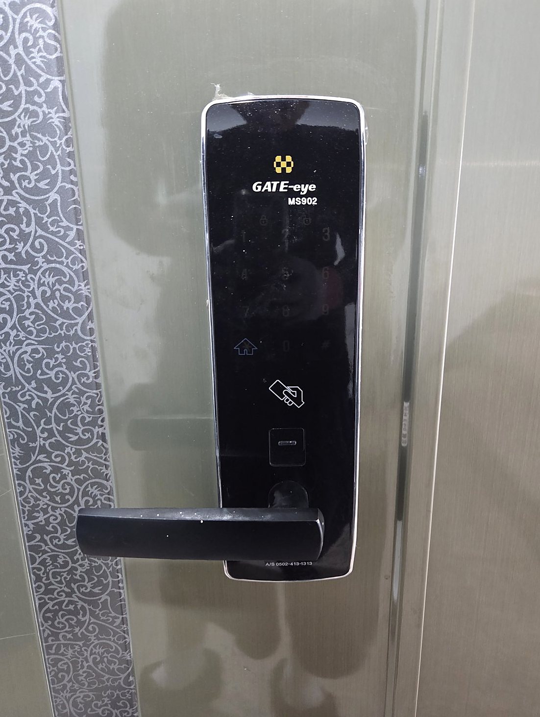 중랑구 면목본동 출장 — 올리브빛 철문에 단 검은 레버형 도어락, 번호판과 카드 표시, 아래쪽 손잡이